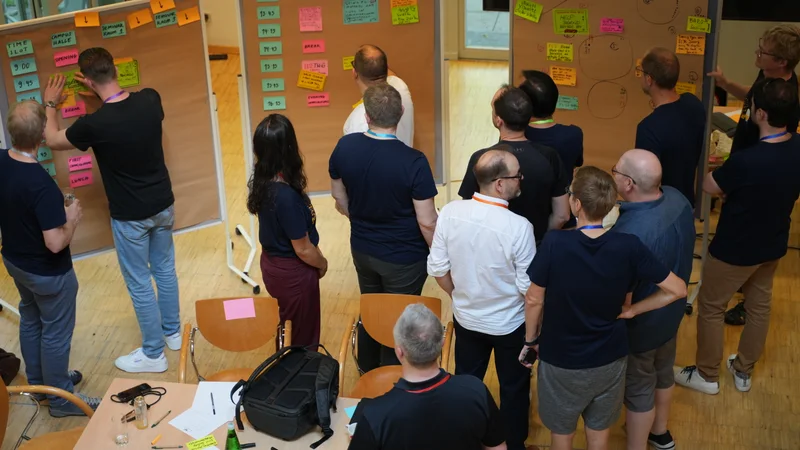 Flight Levels practitioners discussing ideas and arranging sticky notes on session boards
